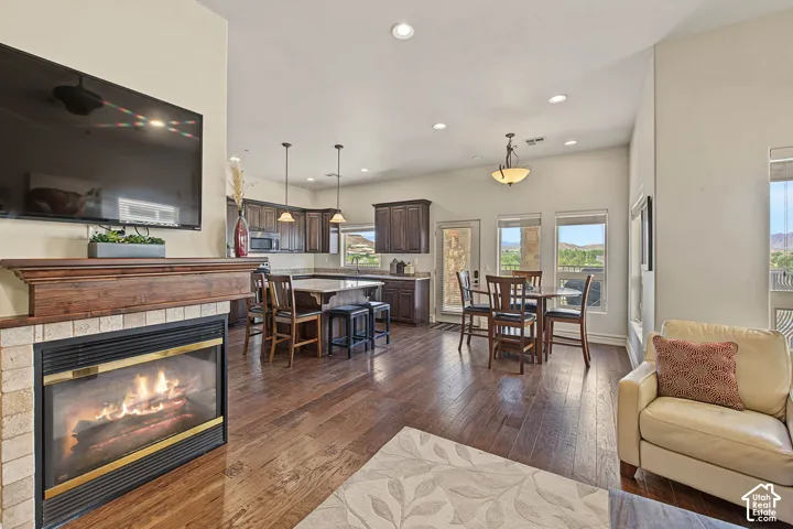 Hardwood-finish flooring throughout, a stone-tiled fireplace with wood mantel, recessed lighting, and a kitchen with dark wood cabinetry and stainless steel appliances