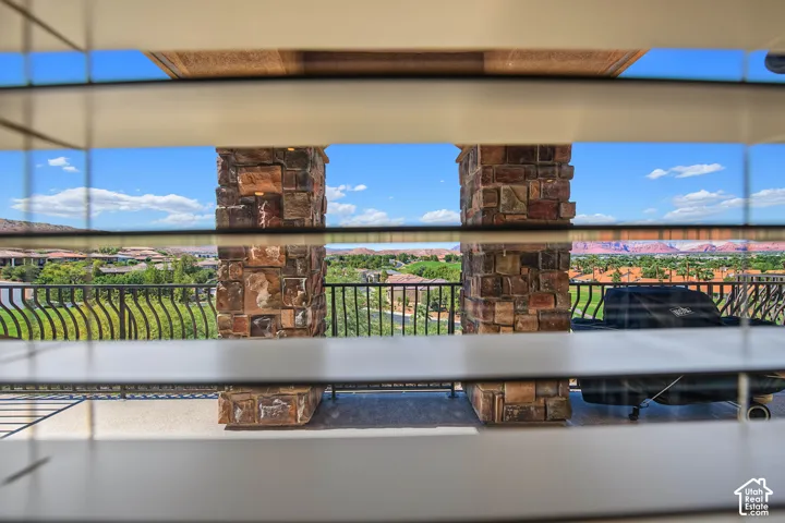Balcony with stone-clad pillars, wrought iron railing, and distant natural scenery
