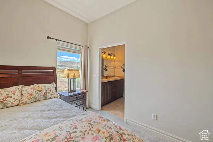Recessed window with blinds and drapes, wood headboard, built-in vanity with sink and mirror, four-light vanity fixture