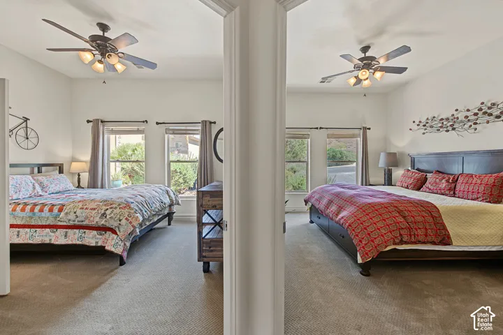 Two distinct areas featuring carpeted flooring, multiple windows with dark curtain rods, and ceiling fans with integrated lighting