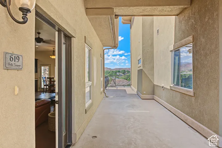 Outdoor balcony with a stucco exterior, sliding glass door entry, and wrought iron railing