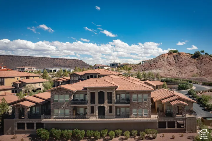 Multi-level residential building featuring stone veneer accents, terracotta-style roof tiles, and multiple balconies