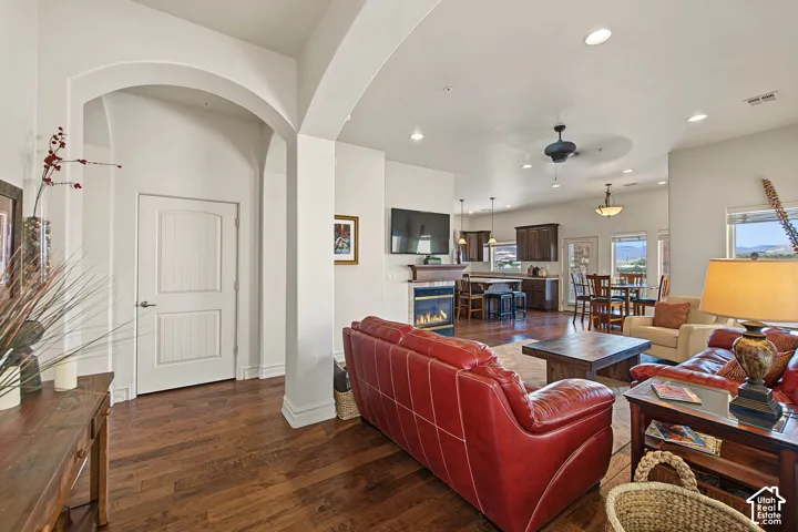 Open-concept living space featuring wood-finish flooring, an arched entryway, recessed lighting, and a built-in fireplace
