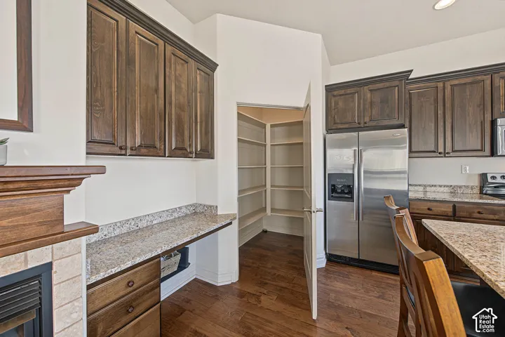 Dark wood cabinetry, granite countertops, stainless steel refrigerator, and a built-in pantry with shelving