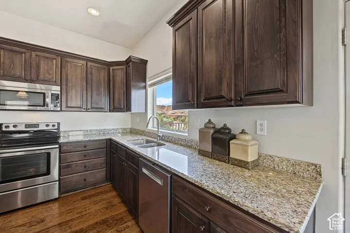 Dark wood-finish cabinetry, stainless steel range, built-in microwave, and dishwasher, and light granite countertops