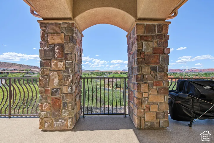 Expansive balcony featuring stone-clad pillars, an arched entryway, decorative metal railings, and a durable floor surface