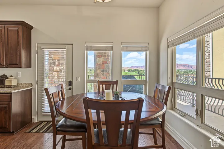 Wood-finish flooring, dark wood cabinetry, granite-style countertops, multiple windows, and a glass-paneled door