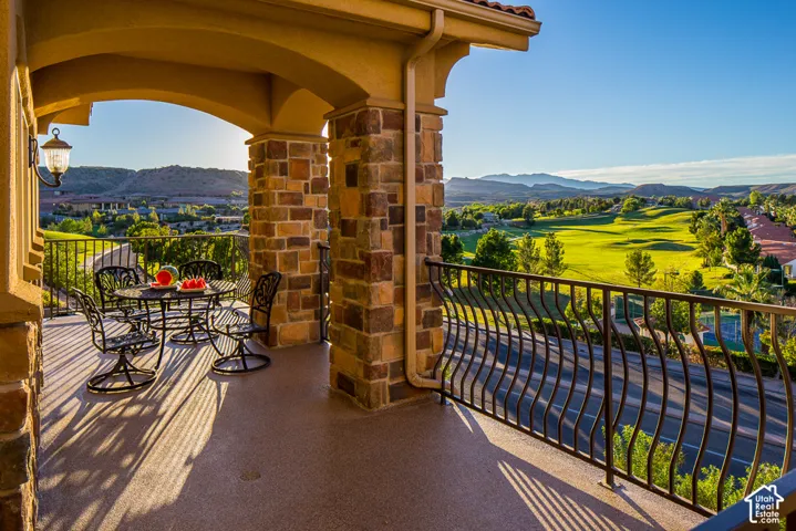 Covered balcony featuring stone-clad pillars, arched openings, and a decorative wrought iron railing