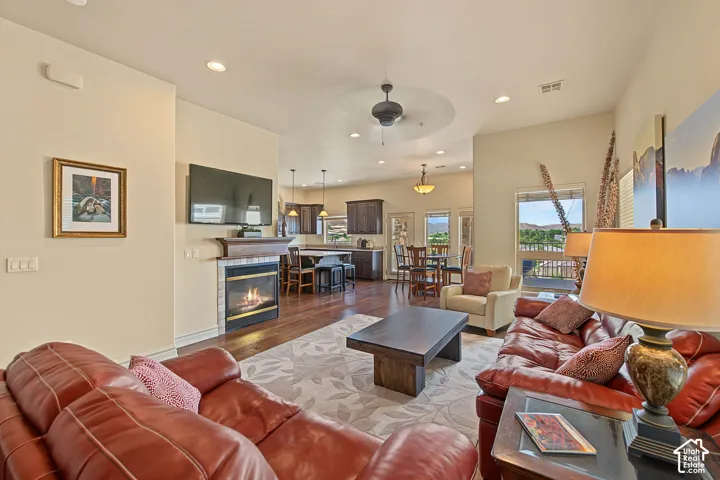 Open concept living area featuring a fireplace with a tile surround and wood mantel, recessed lighting, and wood-finish flooring