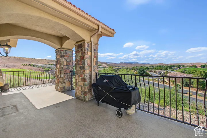 Covered outdoor patio featuring stone-clad columns, an arched entry, and a wrought iron railing