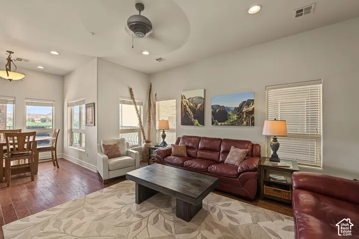 Recessed ceiling lighting, wood-finish flooring, multiple windows with blinds, ceiling fan, and tray ceiling detail