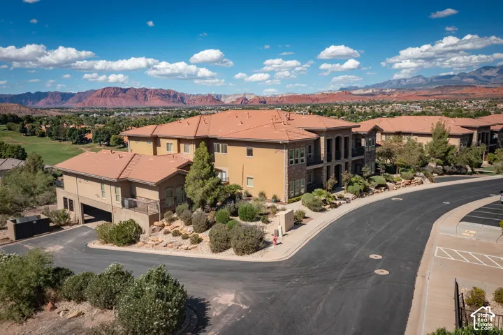 Multi-level residential structures featuring a blend of stucco and stone facades, terra cotta tile roofs, and integrated garages