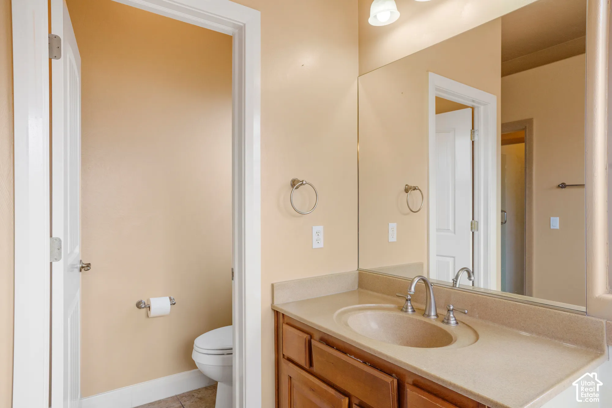 Vanity with integrated sink, brushed nickel faucet, wood-finish cabinetry, and full-width mirror