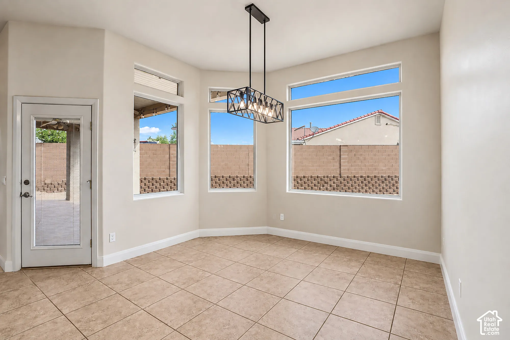 Tiled flooring, white baseboards, a full-lite exterior door, large windows, and a black linear chandelier