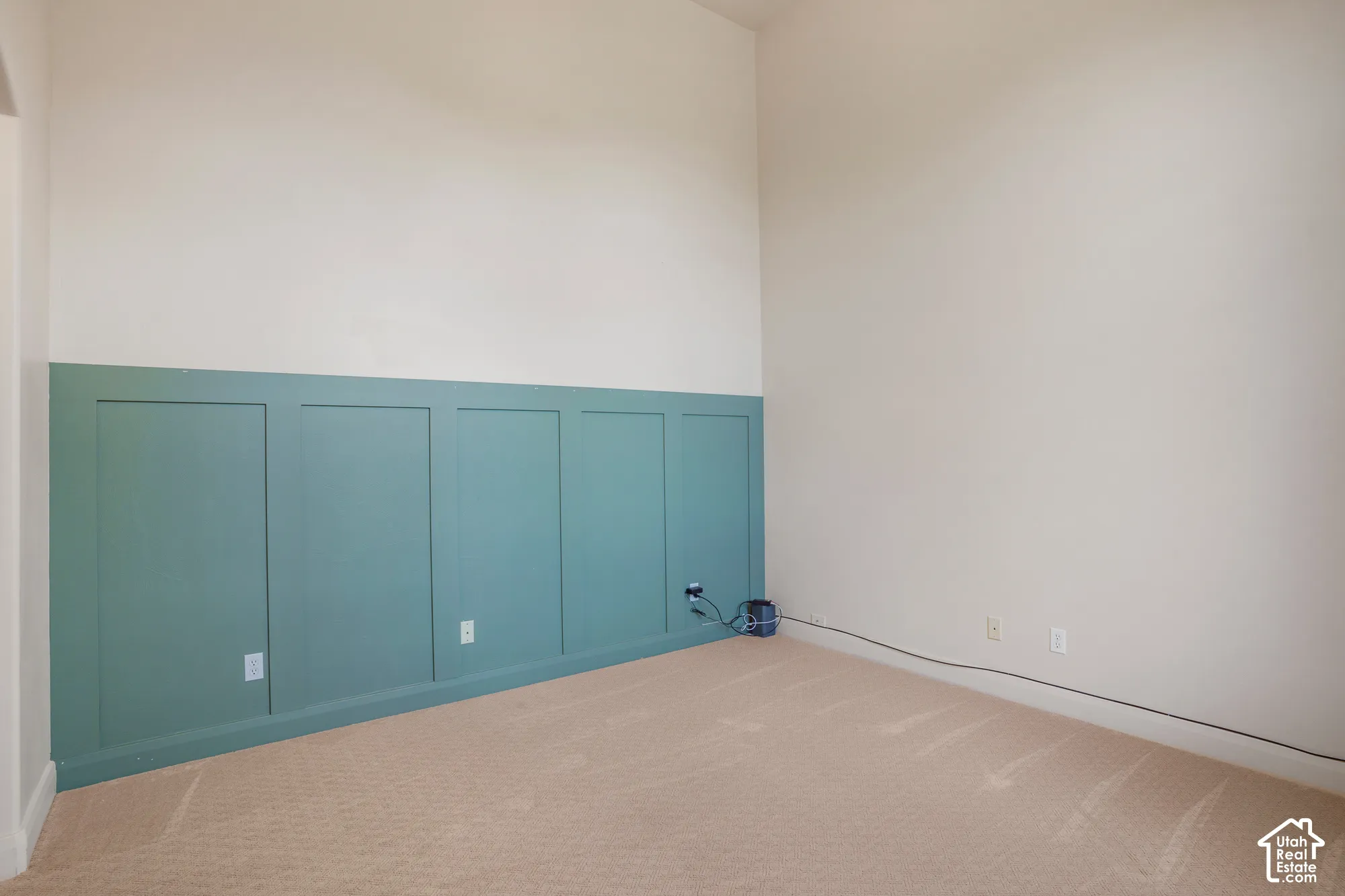Board and batten accent wall, neutral carpet, light-toned wall paint, vaulted ceiling