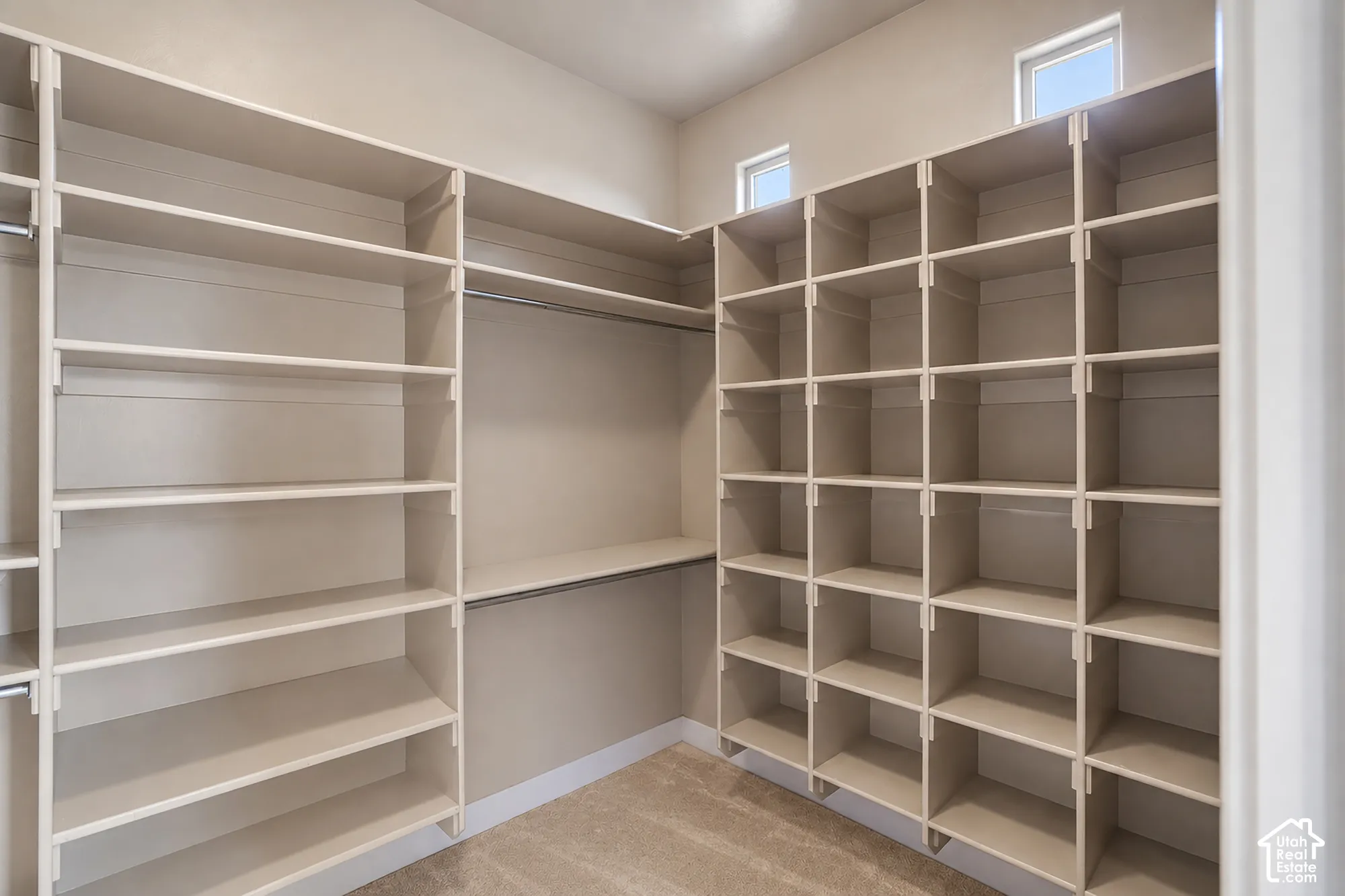 Custom closet system featuring extensive shelving, individual compartments, hanging rods, and high windows