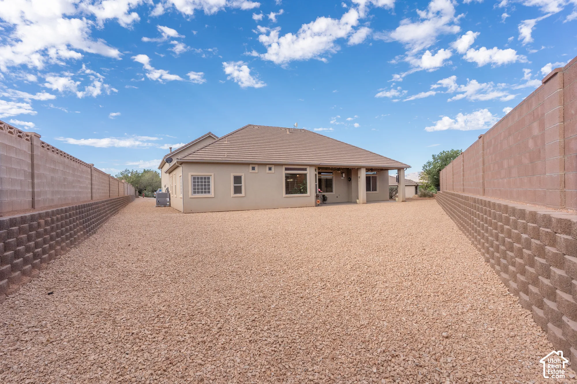 Rear exterior featuring an expansive gravel yard and a covered patio