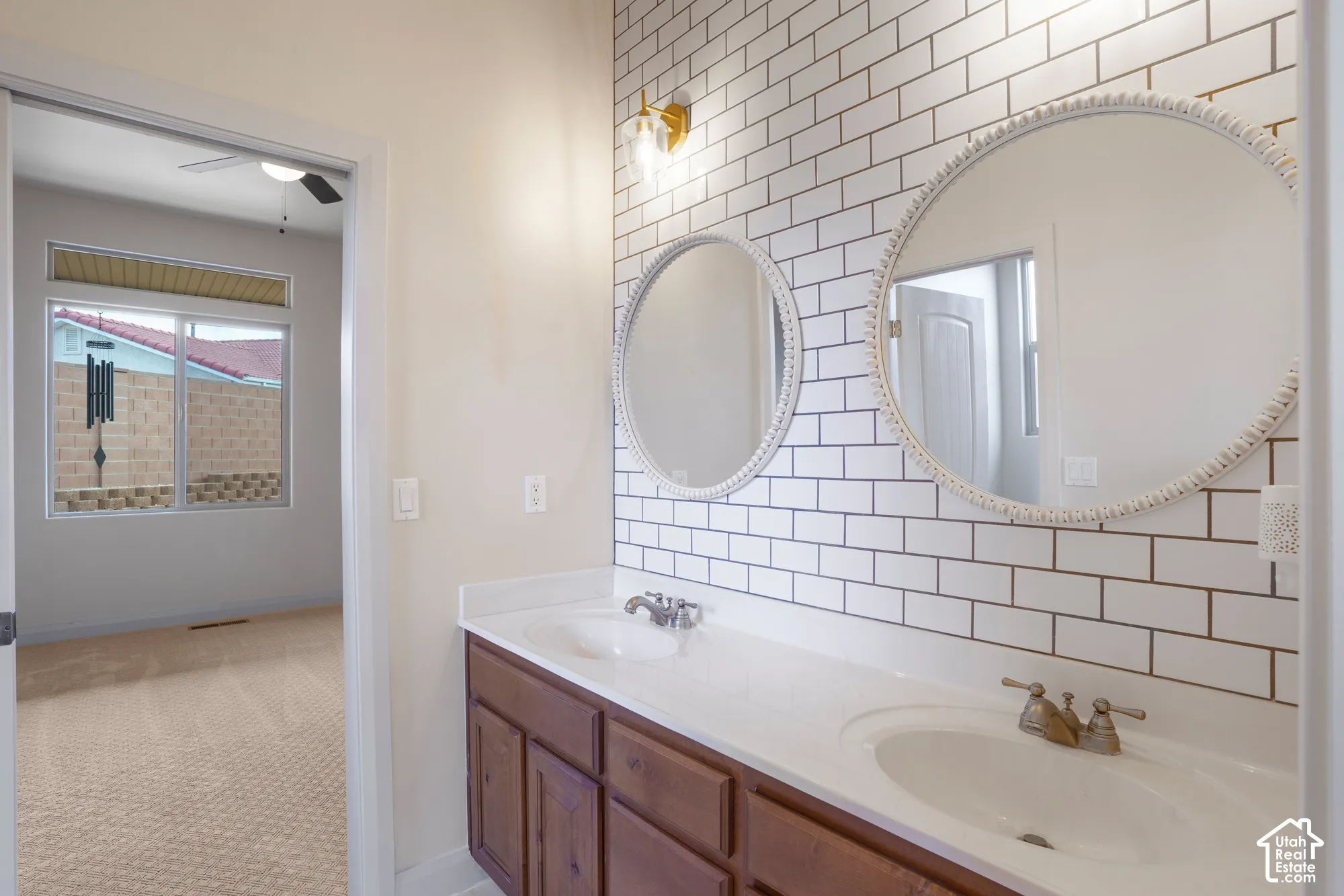 Dual vanity with integrated sinks, subway tile backsplash, and two circular mirrors