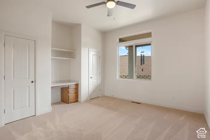 Recessed window with exterior wall framing, built-in desk with drawers, integrated shelving, and a ceiling fan with integrated lighting