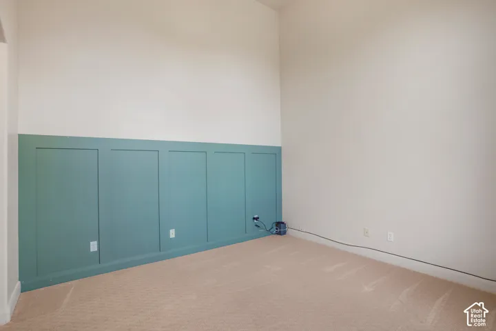 Board and batten accent wall, neutral carpet, light-toned wall paint, vaulted ceiling