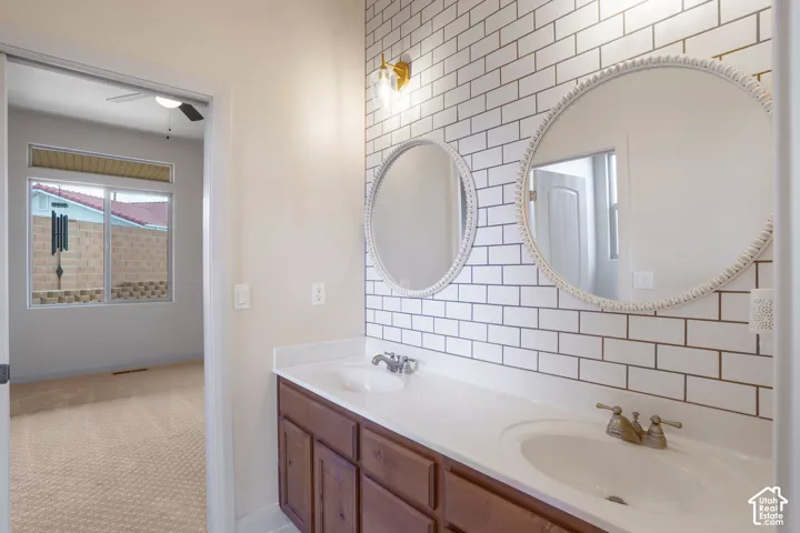 Dual vanity with integrated sinks, subway tile backsplash, and two circular mirrors