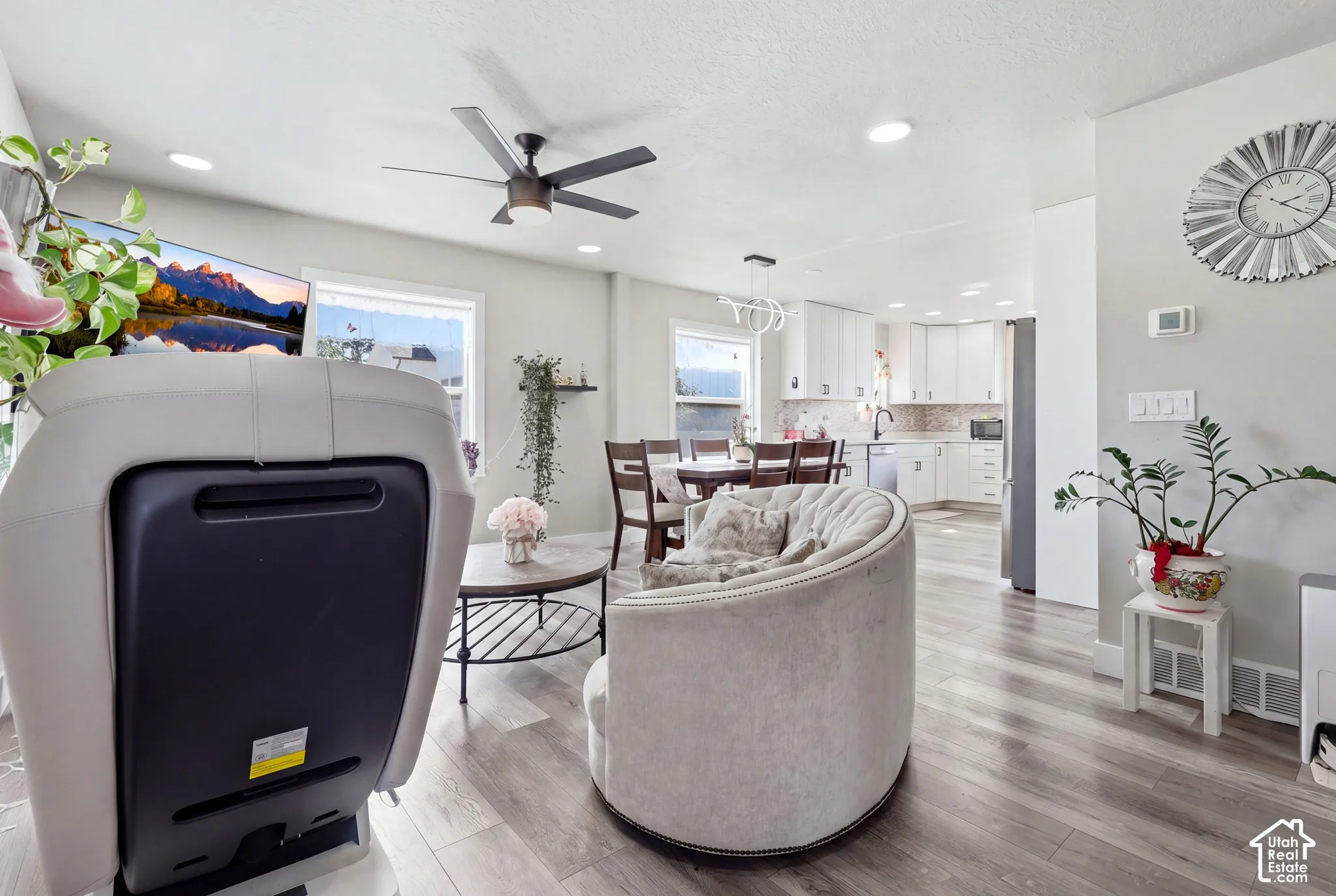 Recessed lighting, wood-finish flooring, ceiling fan, white cabinetry, and stainless steel appliances