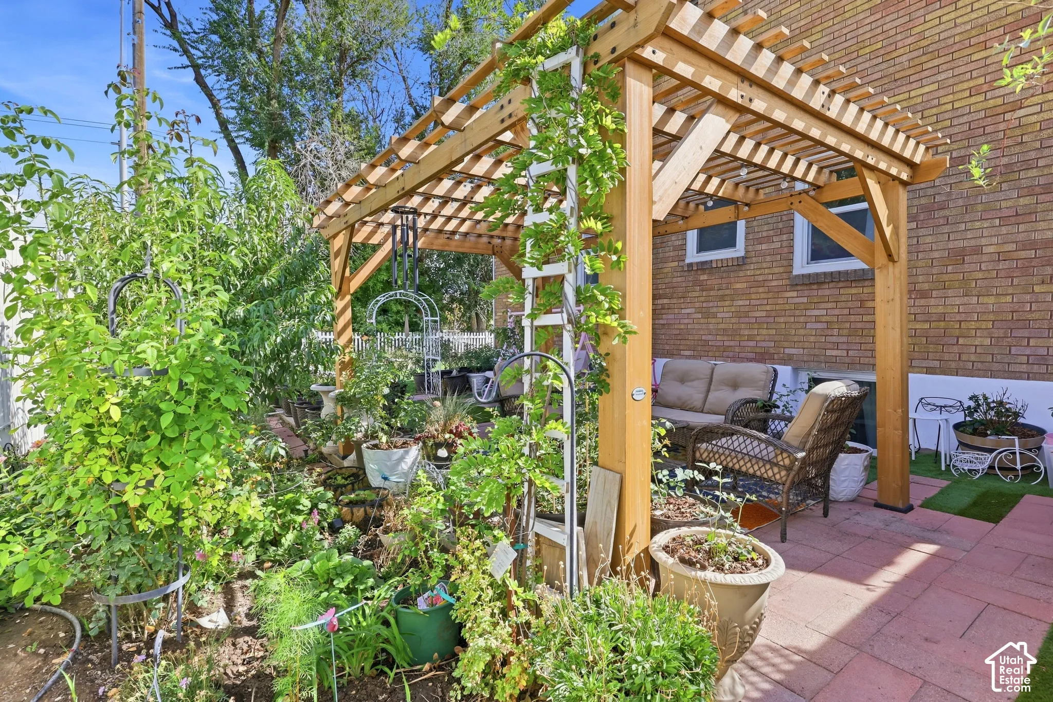 Brick exterior with a wood pergola, paver patio, and extensive landscaping