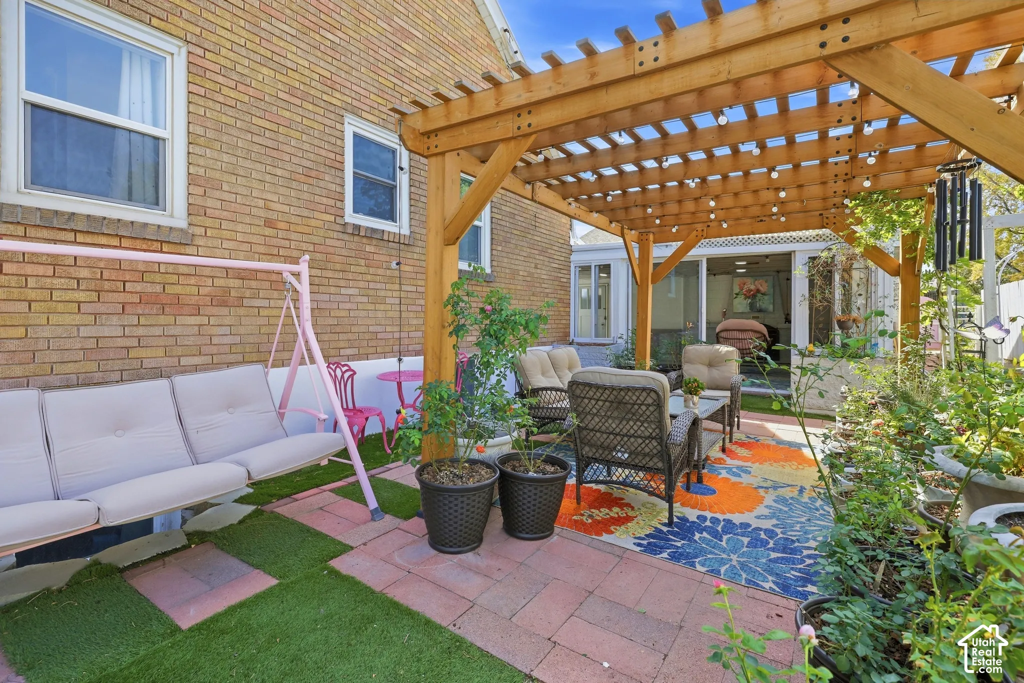 Brick exterior, wood pergola structure, paver patio, artificial turf sections, sliding glass doors