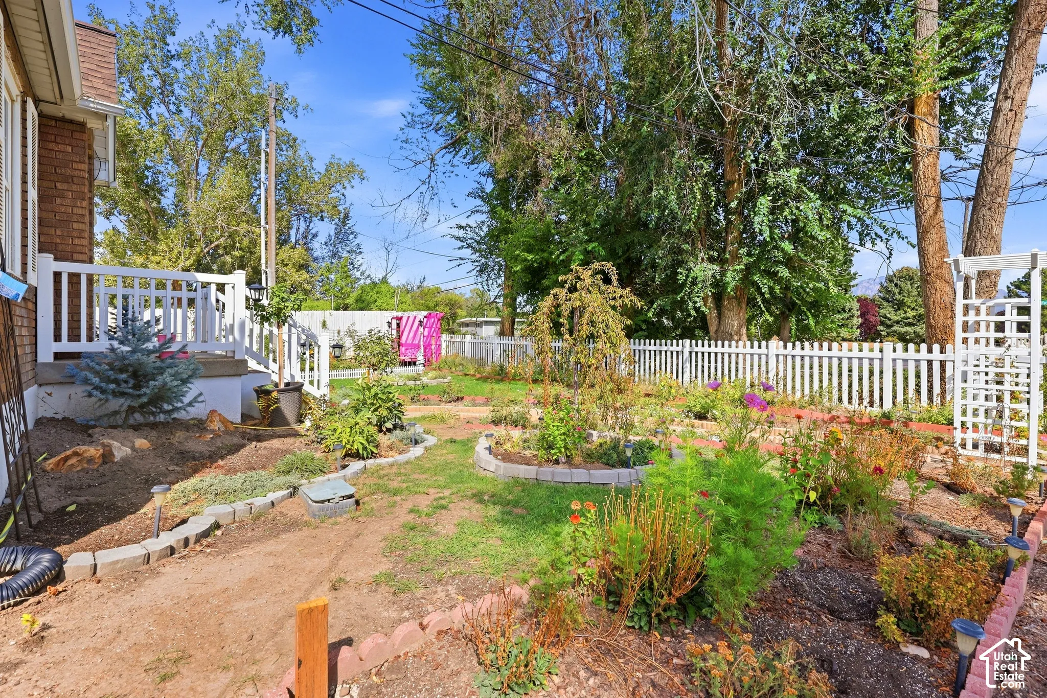 Manicured garden beds, white picket fencing, and a white trellis