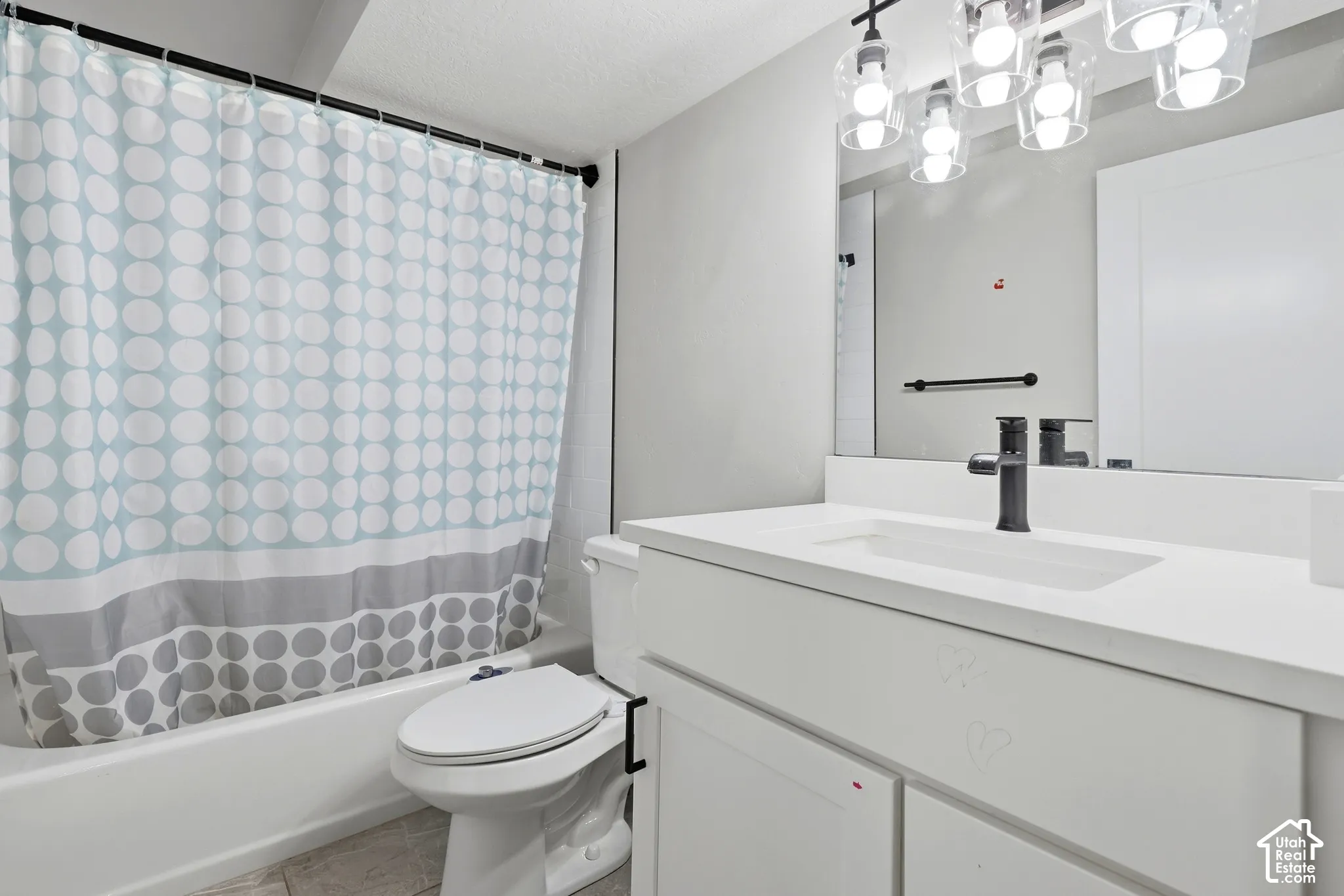 White vanity with integrated sink, black faucet, and overhead lighting fixture