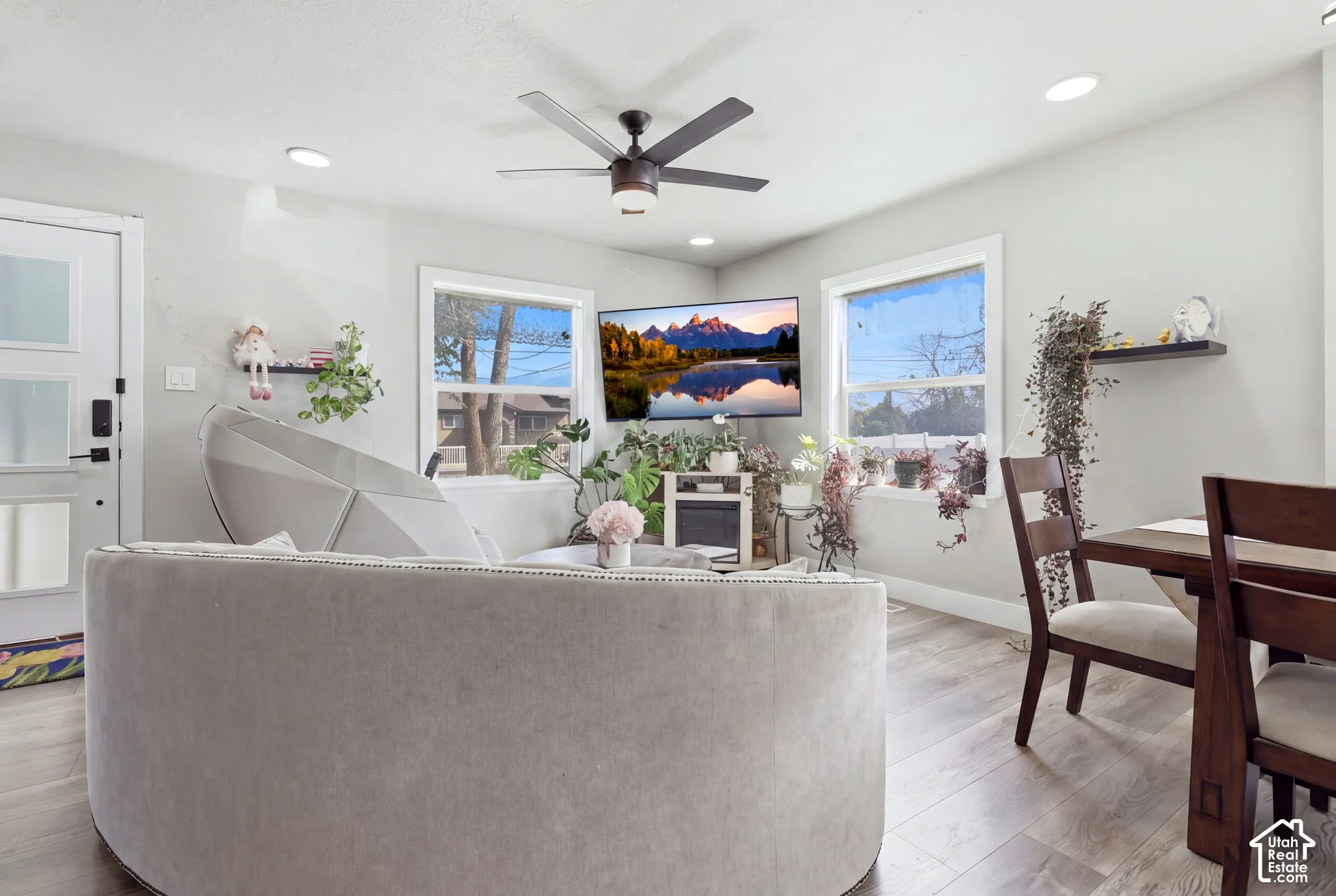 Recessed lighting, wood-finish flooring, white trim windows, and a ceiling fan create a bright interior