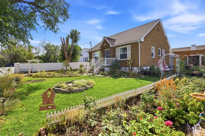 Brick exterior, white picket fence, front porch, mature landscaping, and a side pergola