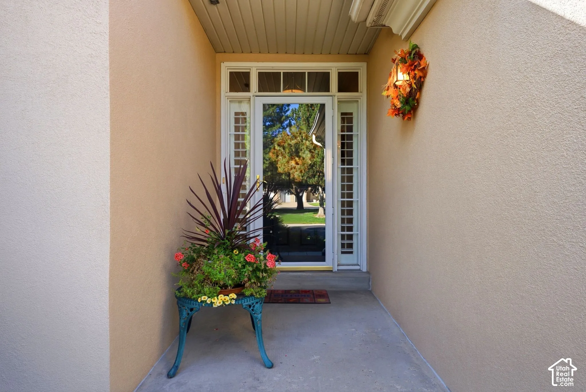 Entryway featuring a white paneled door with sidelights and transom window, stucco exterior, concrete porch, and soffit ceiling