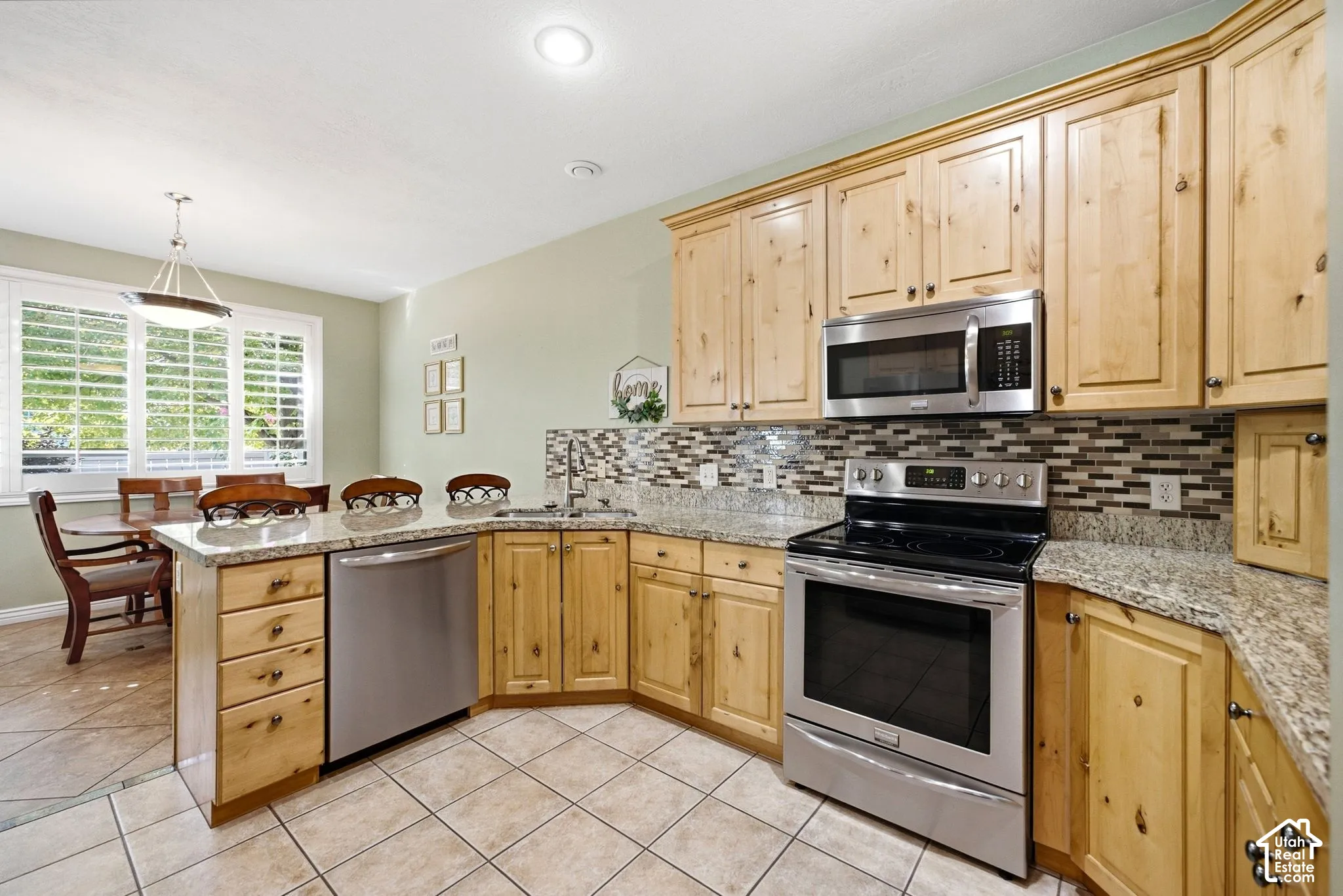 Kitchen featuring light wood cabinetry, granite countertops, tile backsplash, and stainless steel appliances