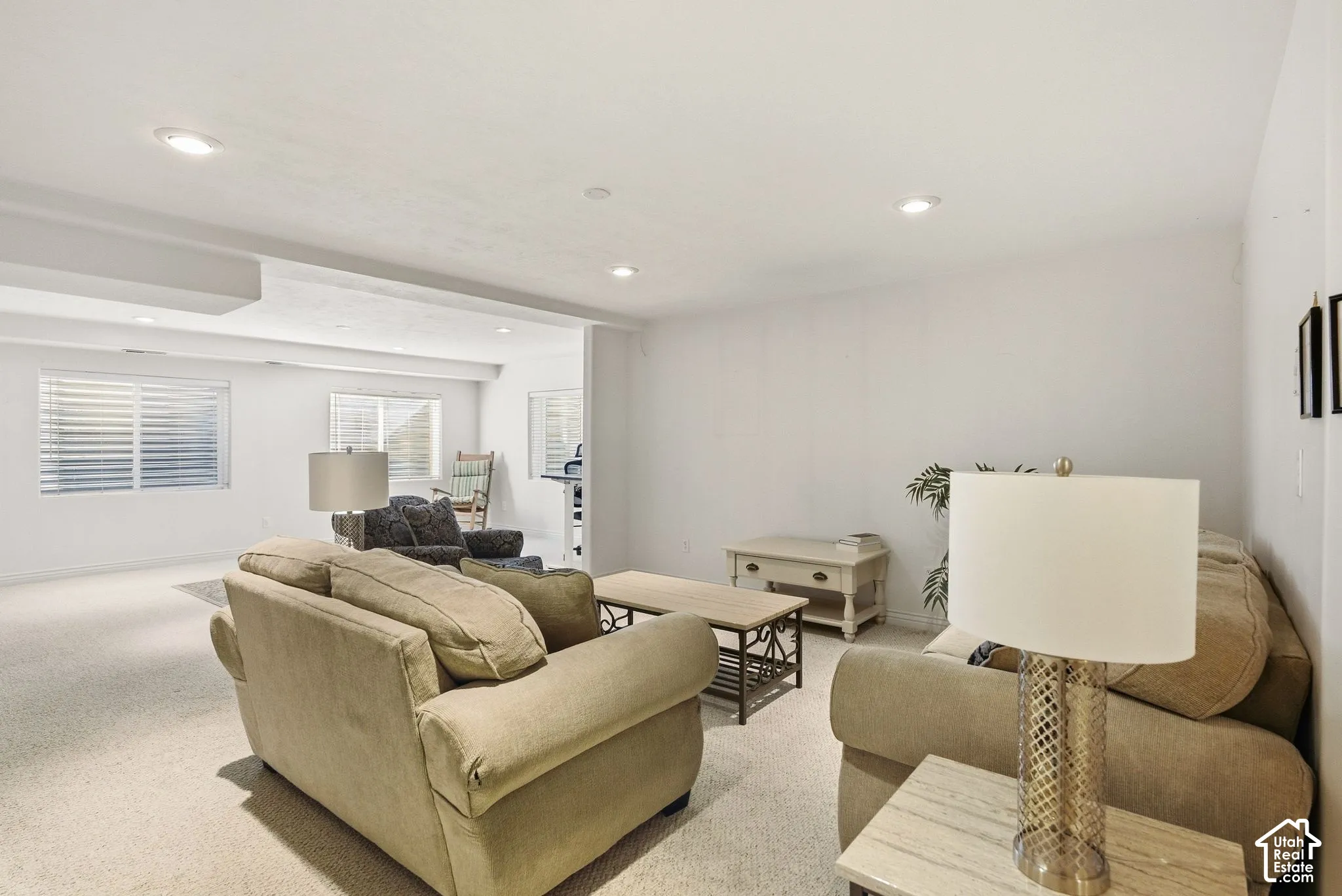 Recessed lighting, white walls, and carpet flooring create a bright atmosphere