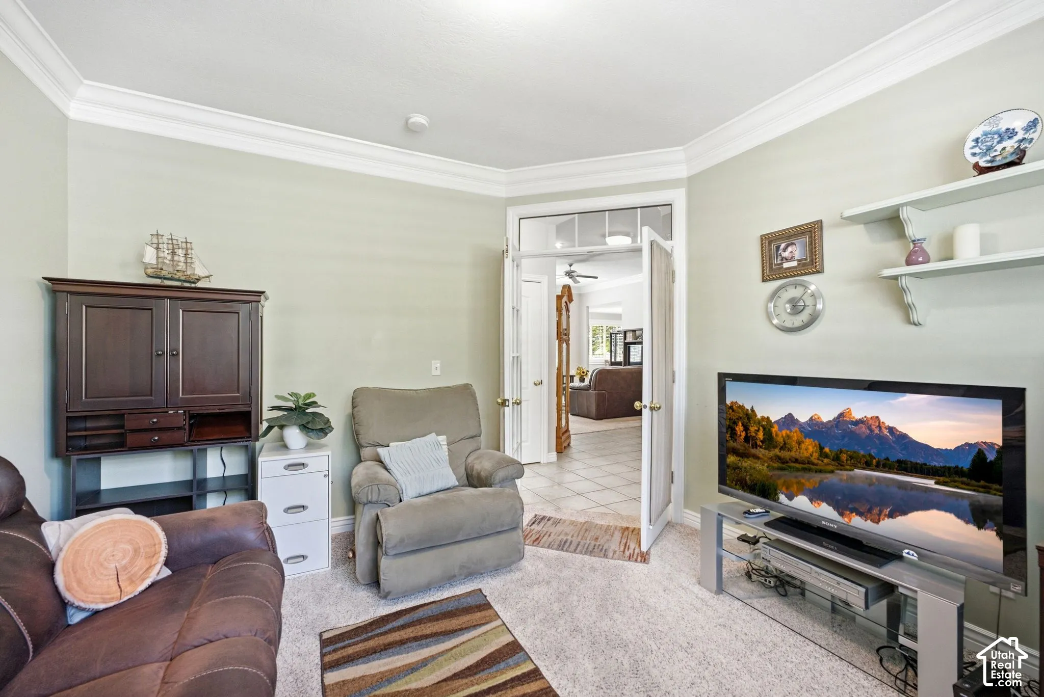 Crown molding with light wall paint, carpeted flooring, and double French doors with a transom window