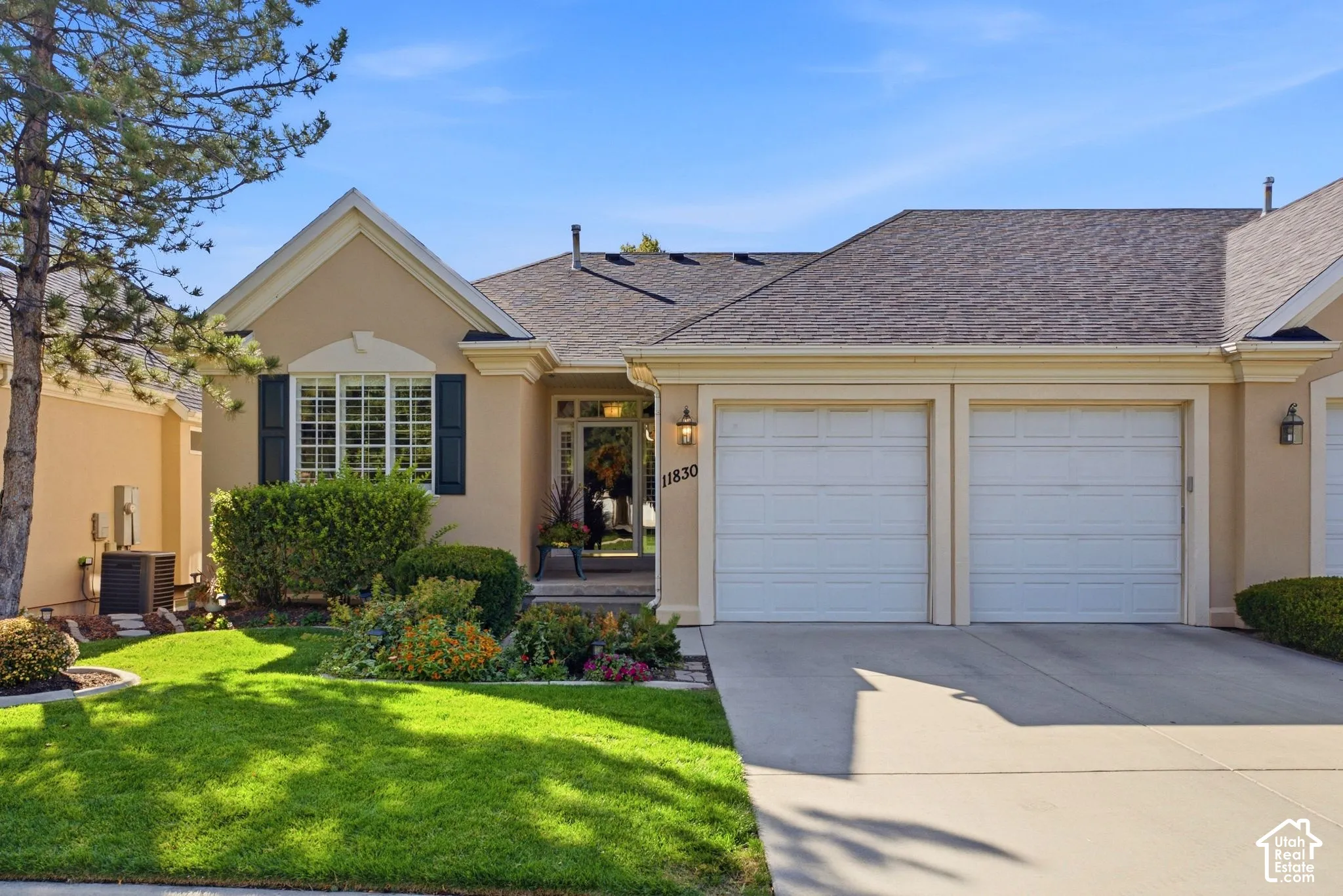 Stucco exterior with a pitched shingle roof, bay window with shutters, and an attached two-car garage