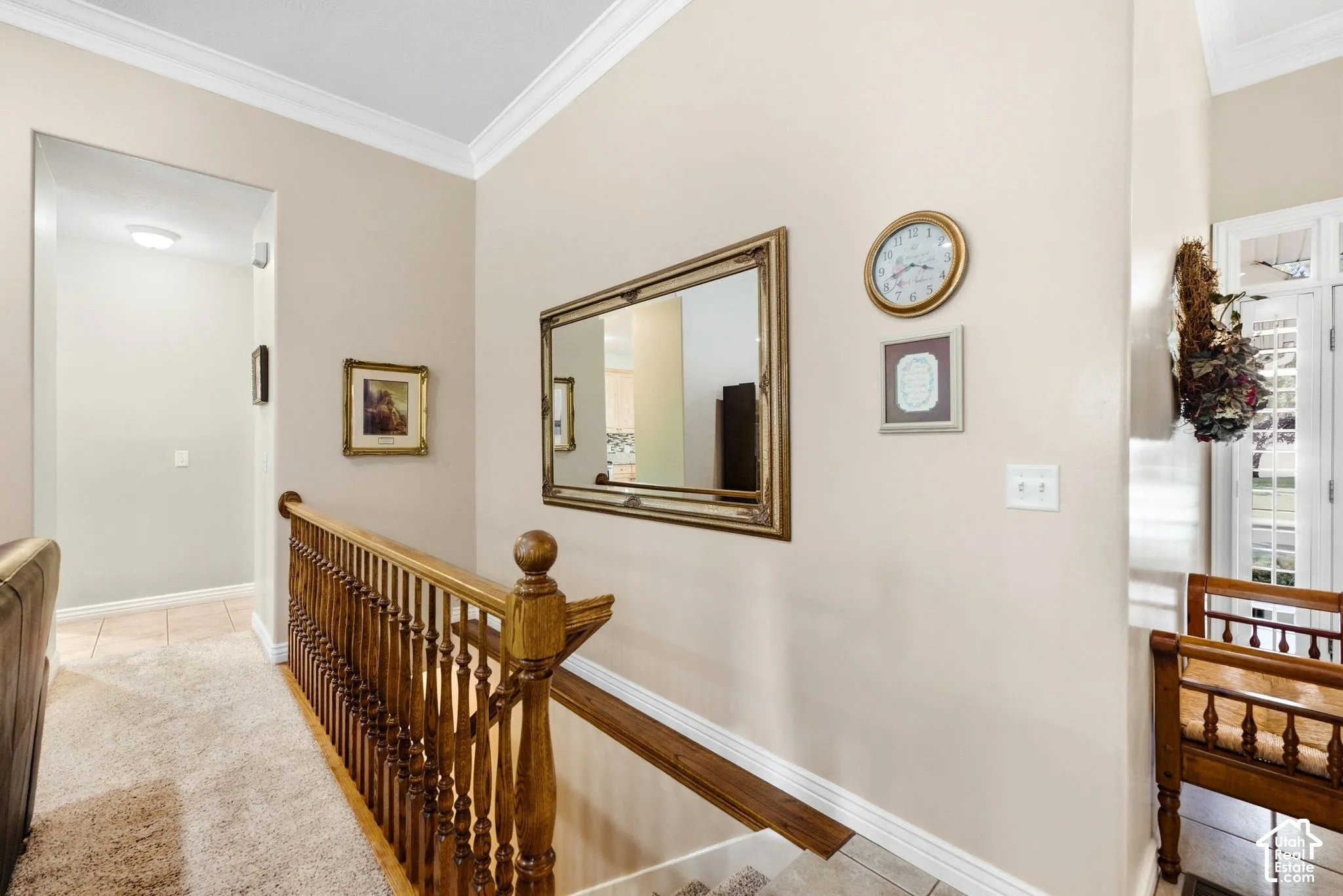 Wood-finish staircase railing with balusters, crown molding, and a light-toned wall finish