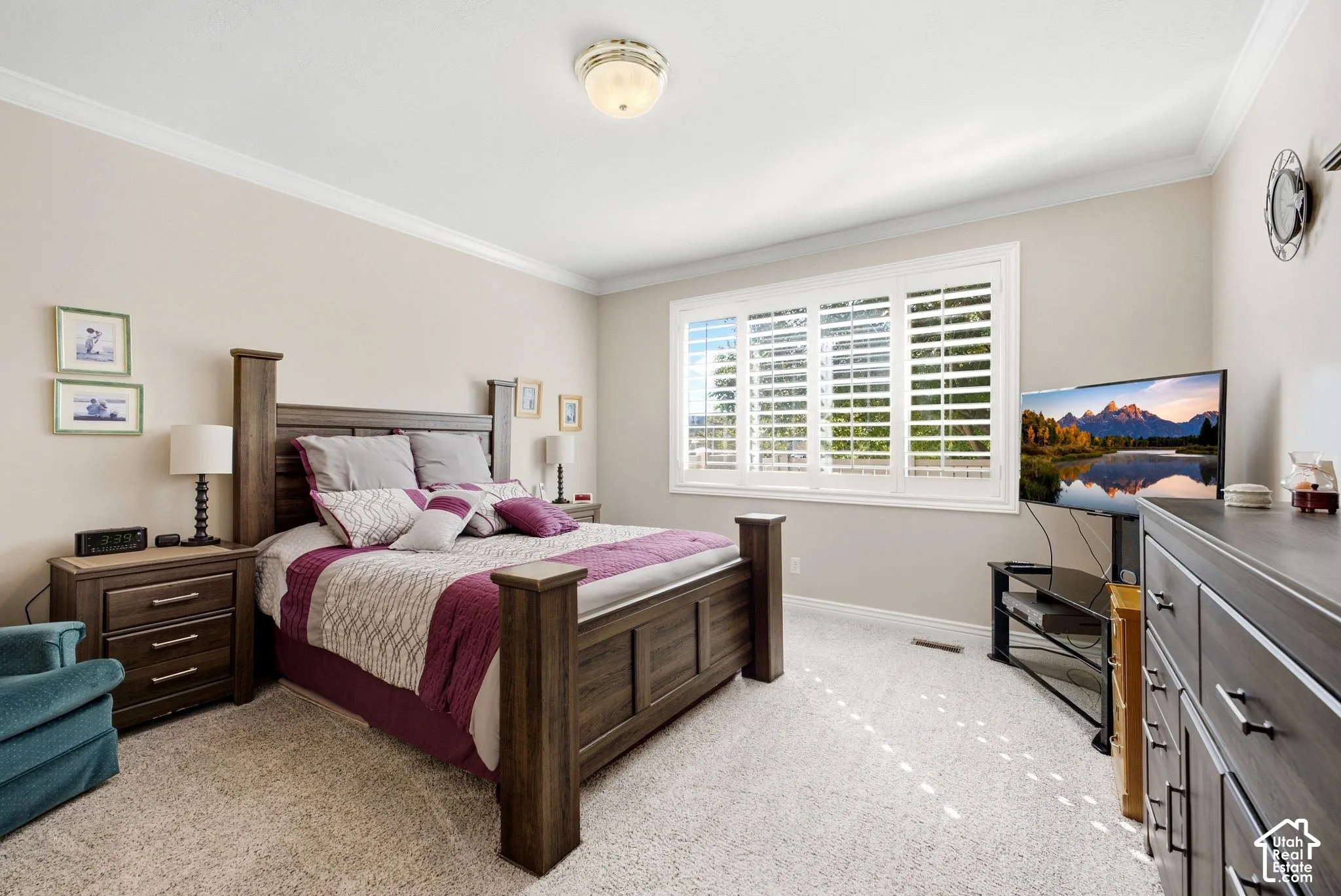 Crown molding, recessed lighting, large window with plantation shutters, and light-toned carpeting