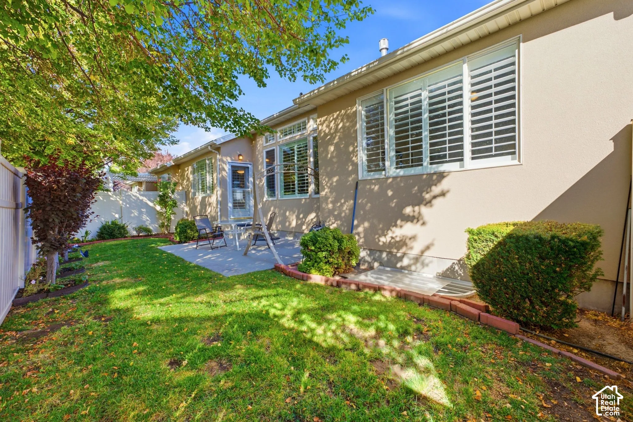 Expansive green lawn with a privacy fence, mature trees, and a concrete patio