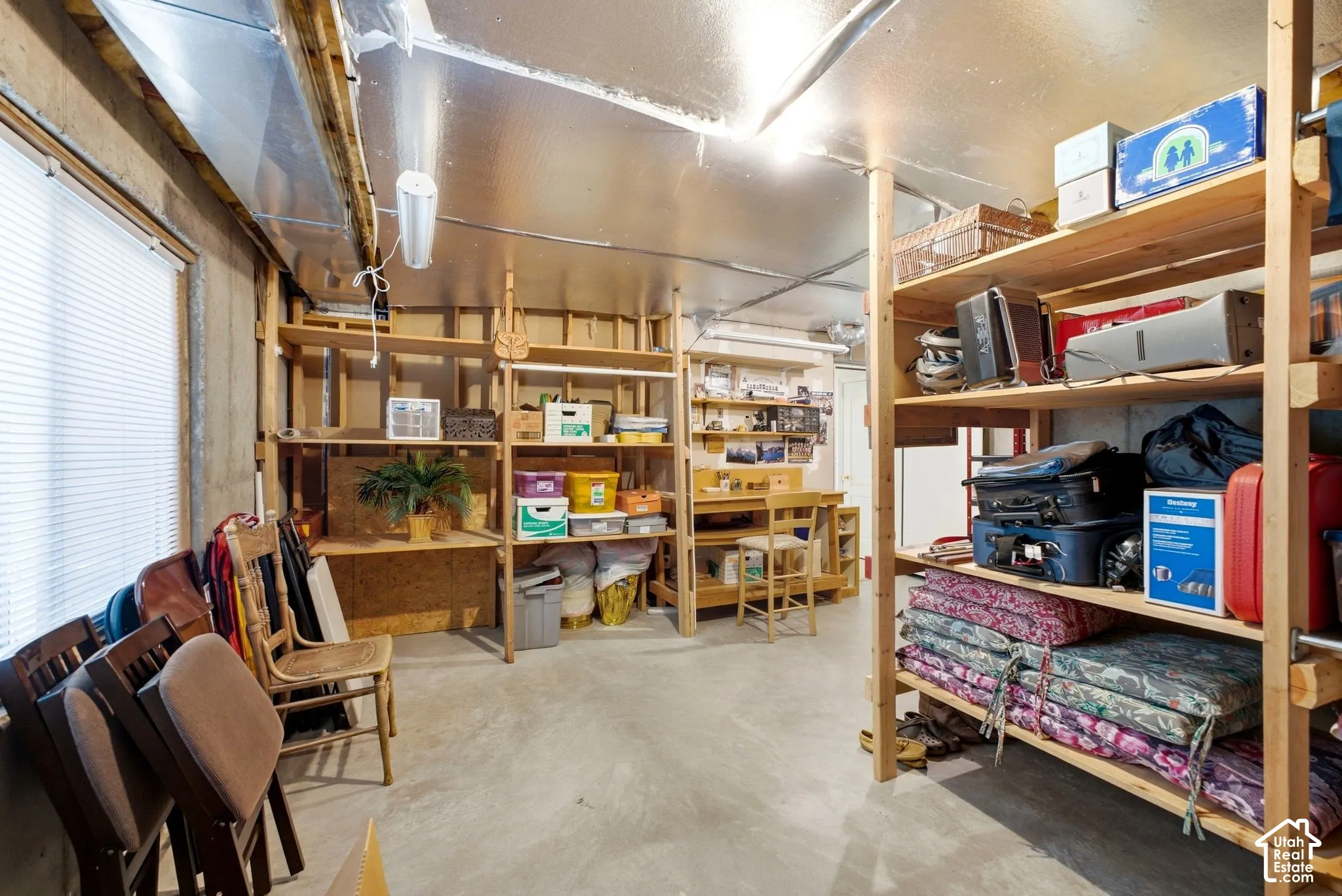 Concrete flooring with exposed ceiling joists and ductwork, illuminated by fluorescent lighting