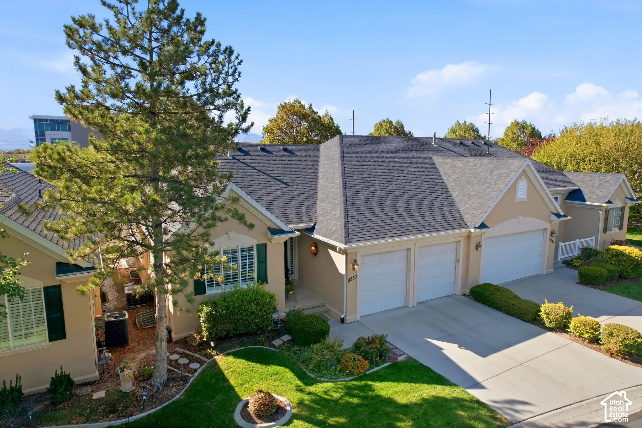 Stucco exterior with a multi-car garage, asphalt shingle roof, and mature landscaping