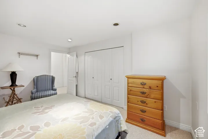 Recessed lighting, white walls, carpeted flooring, and a bi-fold closet door