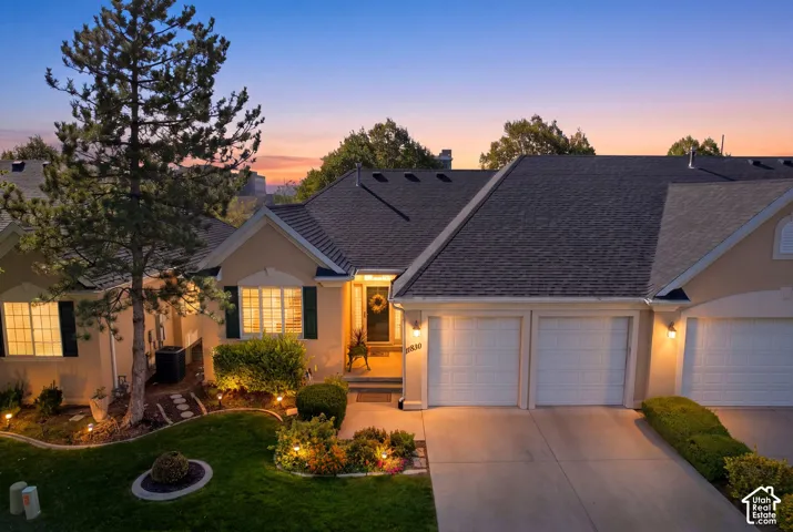 Stucco exterior with a dark asphalt shingle roof, featuring multiple garage doors and a well-maintained front lawn with mature landscaping