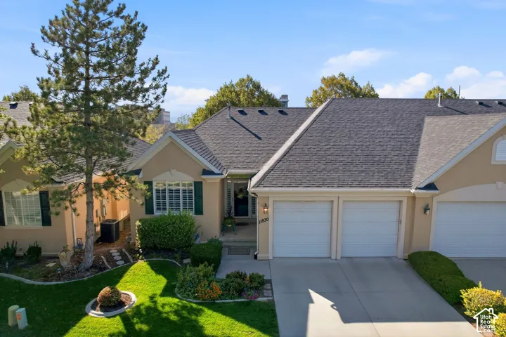 Stucco exterior with a dual garage, dark shingle roof, and white-framed windows
