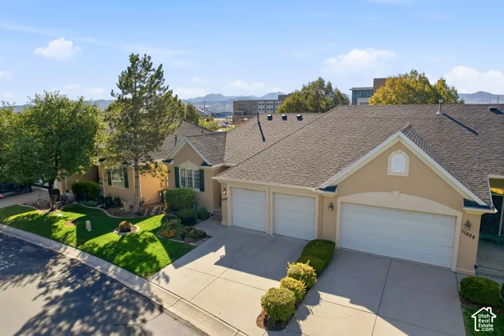 Stucco exterior with a pitched shingle roof, attached two-car garage, and a concrete driveway