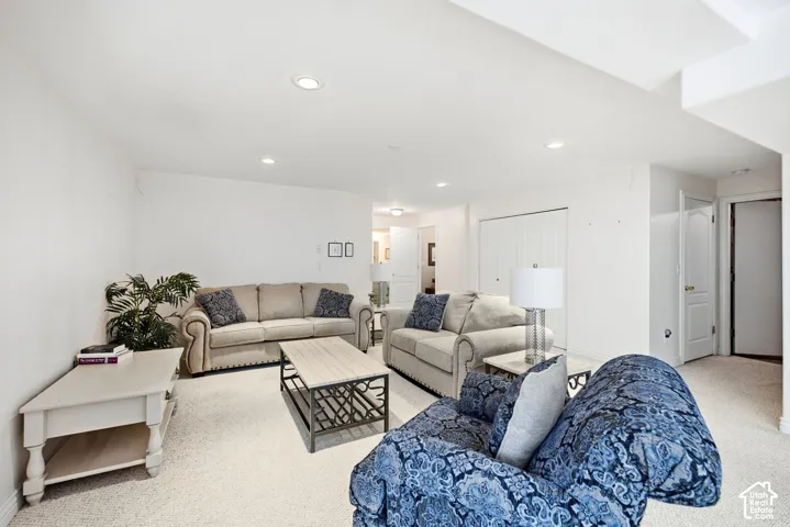 Recessed lighting illuminates a spacious room with light-toned carpeting and white walls