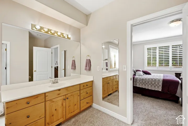 Spacious vanity with light wood cabinetry, a white countertop, and a large wall-mounted mirror