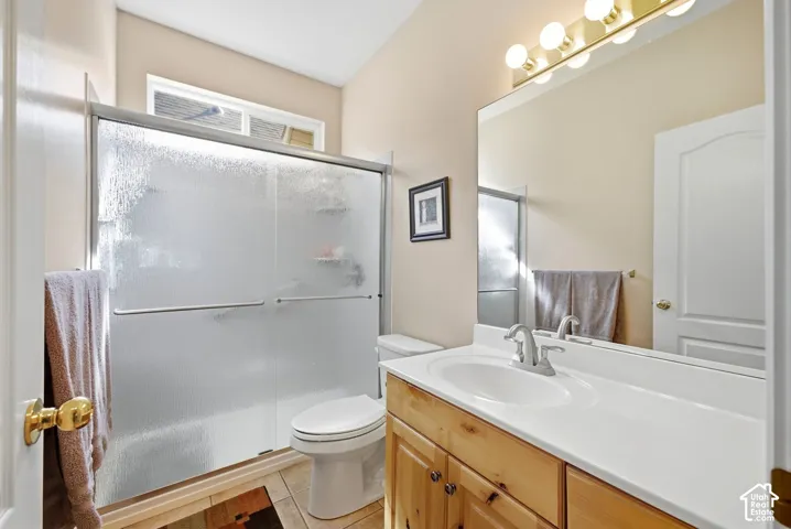 Frosted glass shower enclosure, single vanity with wood-finish cabinetry, integrated sink, and a large wall-mounted mirror