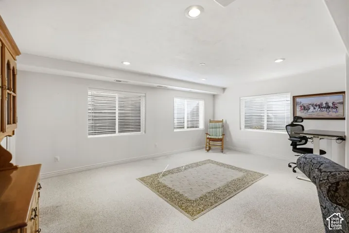 Recessed lighting illuminates the carpeted room with multiple windows